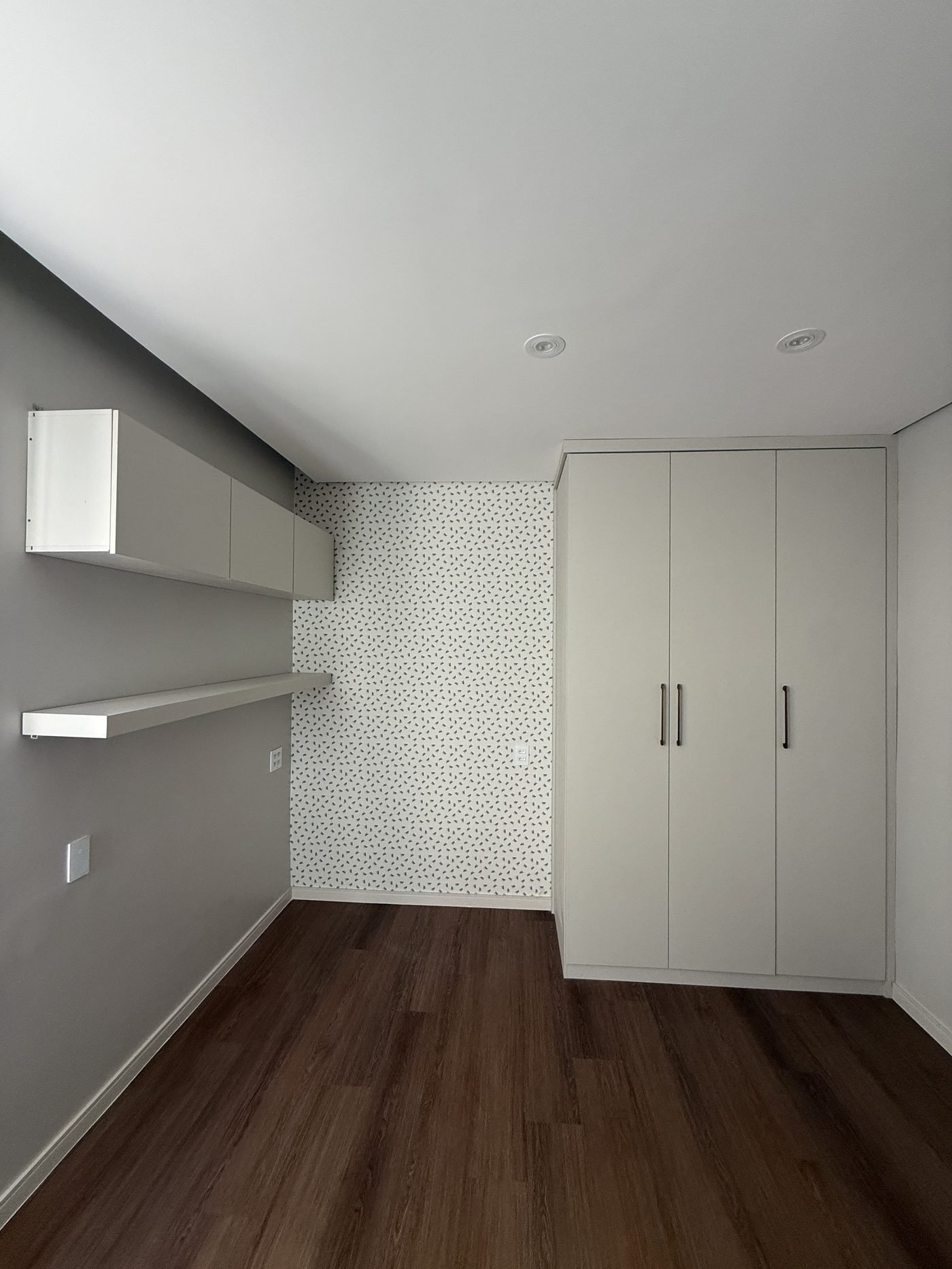 Quarto de apartamento com piso vinílico, marcenaria planejada e papel de parede