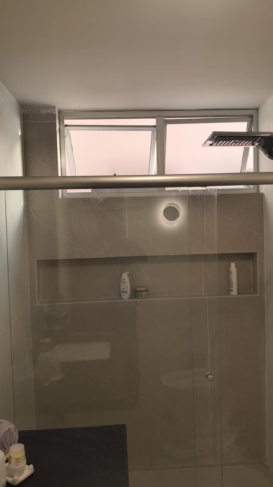 Box de banheiro com porcelanato de grande formato e nicho embutido executado em recorte contínuo do revestimento, obra da Apus Construtora