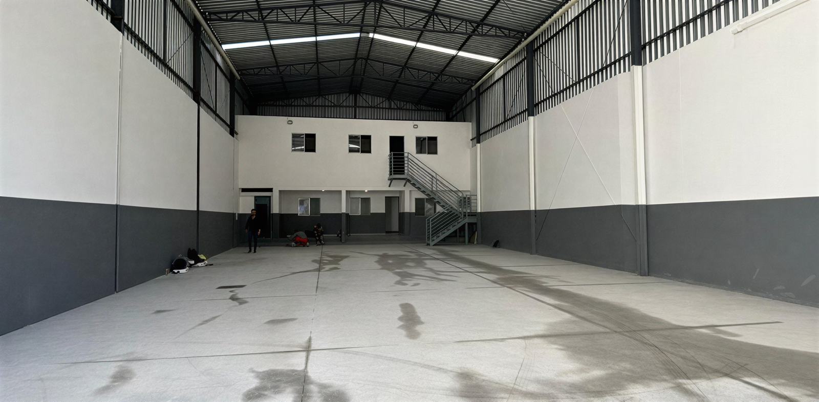 Interior de galpão de 330 metros quadrados em Belo Horizonte, com vão livre integral, cobertura em estrutura metálica e bloco de escritórios em dois níveis, executado pela Apus Construtora